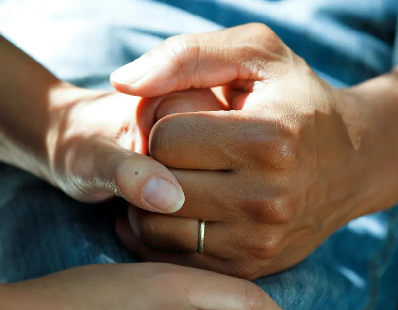 Two people holding hands in support